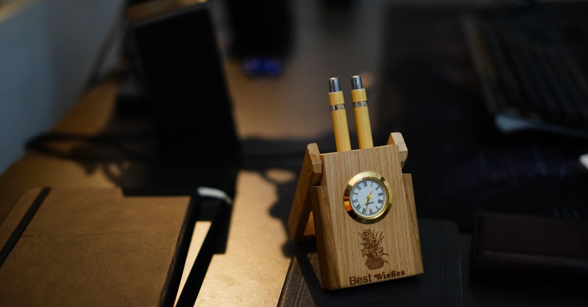 Stylish wooden desk organizer with built-in clock and pens on a modern office desk.
